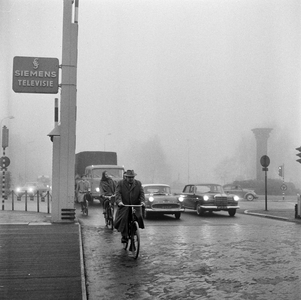 125611 Afbeelding van het verkeer bij de rotonde op het Leidseveer te Utrecht, vanaf de Catharijnebrug, tijdens mist.